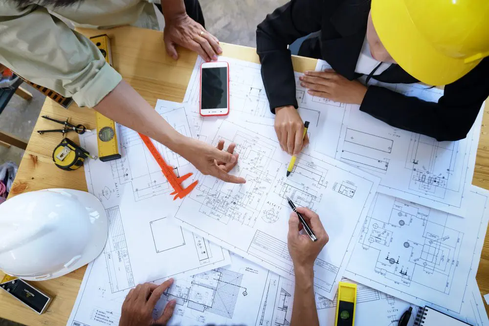 A group of people sitting around a table with construction plans.